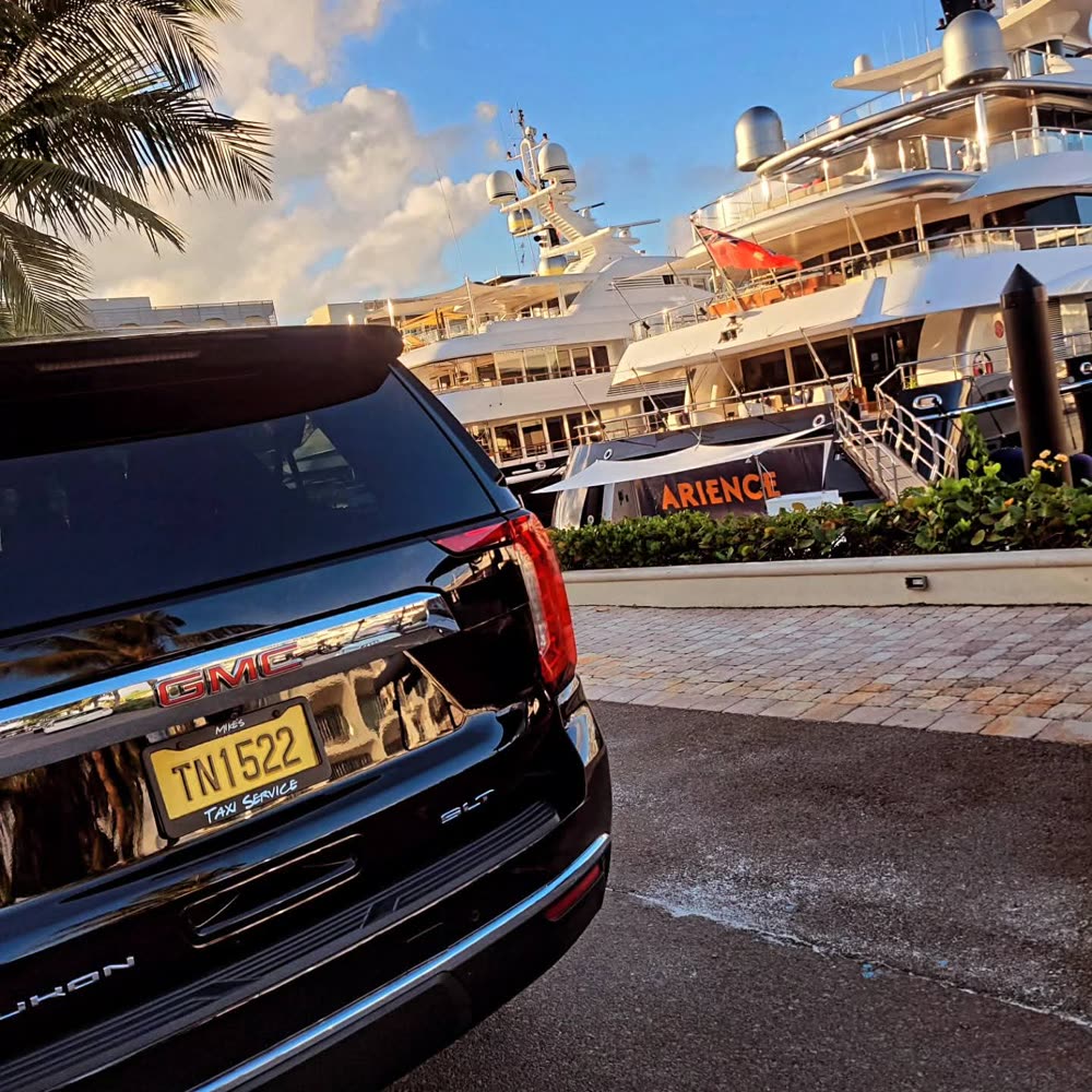 Mike's black GMC Yukon, plate TN1522, parked beside superyachts at a Nassau marina